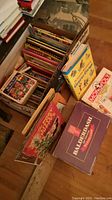 Box containing various children's story and fairy tale books along with board games visible including Junior Monopoly and Balderdash.