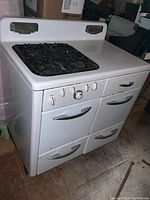 Front and side angled view of the vintage Robertshaw gas stove showing four burners, control knobs, oven doors, drawers, and chrome handles.