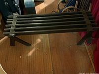 Full view of the wooden slatted plant bench showing the length and slatted top surface.