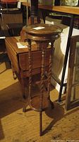 Full view of wood spindle barley twist two tier plant stand showing tall narrow structure and circular shelves