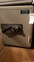 Front view of the safe showing the door, handle, and a label indicating sales and service info.