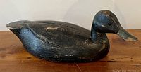 Full side profile of carved wooden duck decoy on tabletop