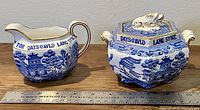 Front view of cream and sugar set with ruler for scale showing blue and white pattern and gold trim