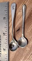 Top view of two sterling silver salt spoons alongside a ruler, showing size approx. 2.5 inches.