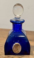 Front view of cobalt blue glass bottle with clear glass spherical stopper and sterling silver frontispiece.
