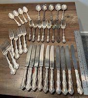 Full set spread out on table, including forks, knives, spoons, ladles with ornate Regency Plate patterned handles.