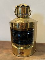 Front view of the vintage brass boat light showing polished brass body and blue glass lens with a small plate marking 'Sturdo...'.