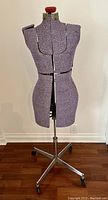 Full view of the vintage dress form mannequin upholstered in textured purple fabric with adjustable torso panels.