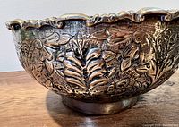 Side view of bowl showing fish and leaf motifs and scalloped rim detail.
