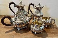 Full set showing all five pieces: water pot, tea pot, coffee pot, cream pitcher, and sugar bowl arranged on a wooden surface.