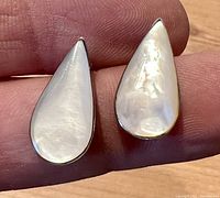 Close-up of front showing teardrop-shaped pearl with reflective, luminous surface in silver setting.