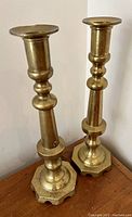 Pair of vintage tall heavy brass candlesticks with hexagonal scalloped bases and decorative stems.