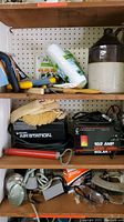 Shelf with Black and Decker air pump, battery charger, whiskey jug, polishing pads, and various brushes and rollers.