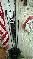 Photo showing two flags hanging on poles, various ski poles bundled in a black container.