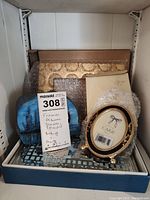 Photo of assorted picture frames, baby album, and package with oval picture frame showing bird design on front