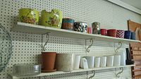 Shelves holding multiple planters and vases in ceramic, clay, glass, and metal materials mainly in colors like yellow, green, blue, red, white, and metallics.