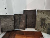 Four rectangular wooden etching blocks with visible carved etching of various designs, placed standing up against a wall.