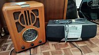 Photo showing front view of vintage Thomas wooden radio and Sony black boombox with attached power cord.