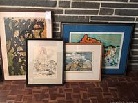 Group of four framed prints displayed against a brick wall