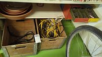 Two wooden crates with metal edges containing yellow and black extension cords, beside a bicycle wheel