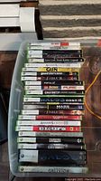 Clear top-down view of stack of Xbox 360 game cases showing titles from Tony Hawk's Project 8 to Grand Theft Auto IV.