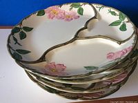Stack of four Franciscan Ware divided dinner plates showing floral design and gold trim.