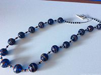 Blue glass bead necklace laid flat showing bead pattern and silver toggle clasp.
