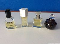 Four mini vintage perfume bottles placed side by side on a blue surface showing front labels and bottle designs.