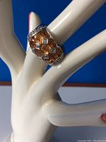 Ring displayed on finger-shaped stand showing front design and stone arrangement