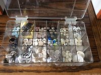 Top-down view of plastic compartment box with various vintage buttons sorted in twenty compartments.