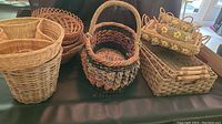 Seventeen woven baskets arranged on a table showing variety in shapes and sizes including nesting and handled varieties.