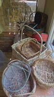 Photo showing a cluster of wicker baskets varying in size and materials, including a metal wire basket and painted wooden basket.