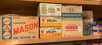 Various boxes of home canning jars and jelly jars stacked, showing Canadian Mason, Bernardin Harvest Mason, Bernardin jelly, Consumer Glass jelly jars, Dominion Mason jars