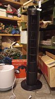 Black Seville Classics 41" oscillating tower fan on floor near shelves