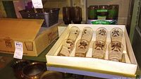 Wide shot of assorted glasses including boxed curling glasses, green Libbey St. Clair glasses and brown tinted glasses in cardboard box and loose