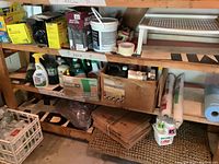 Shelf containing various garden and outdoor products including plant food, insect fogger, outdoor cleaner, plant protection wrap, propane tanks, and other supplies.
