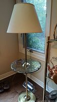 Full view of the floor lamp with built-in glass table, showing its overall design, lampshade, pole, base and glass table surface.