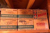 Front view of six cardboard boxes of Dominion Mason and Canadian Mason jars labeled with '1 Dozen Medium' and 'Top Shelf' notes, showing the brand and company names.