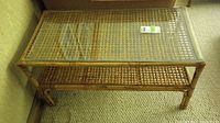 Full view of bamboo and rattan coffee table showing removable glass top and woven lower shelf