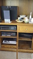 Photo of entertainment cabinet with audio equipment including speakers, cassette deck, CD player, and receiver.