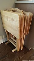 Side view of four wooden folding tray tables on a wooden base carrier.