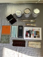 Full view of chalk paint set laid out on gray cloth including paints, brushes, colour card, and wood samples.