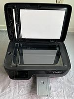 Front open view showing the scanner glass and input paper tray inside the scanner lid.