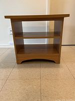 Small wood veneer table seen from the front, showing a rectangular form with one shelf below the top surface.