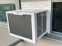 Side view of the NOMA window air conditioning unit installed in window opening with foam and weather stripping visible at the edges.