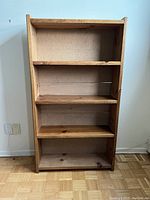 Front view of wooden bookcase showing four shelves and particleboard backing