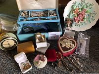 Overhead view of blue jewelry box filled with jewelry, watches, clock and decorative boxes on carpet