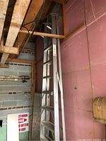 Full view of the aluminum ladder leaning against wall in storage area.