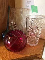 Four glass vases grouped together on wood surface against wood background.