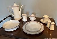 Photo showing all items in the porcelain dinnerware set arranged on a wooden table.